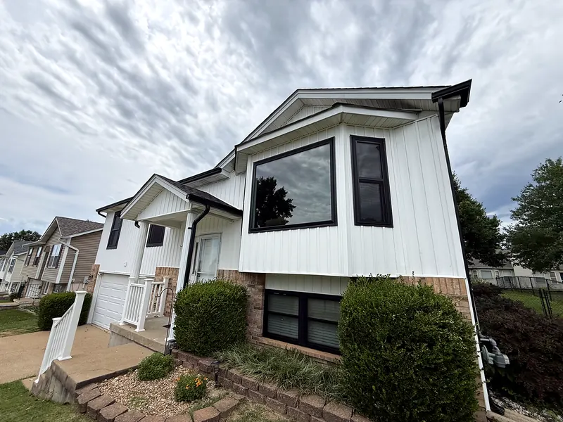Split-level home with new white vertical board and batten siding and black windows