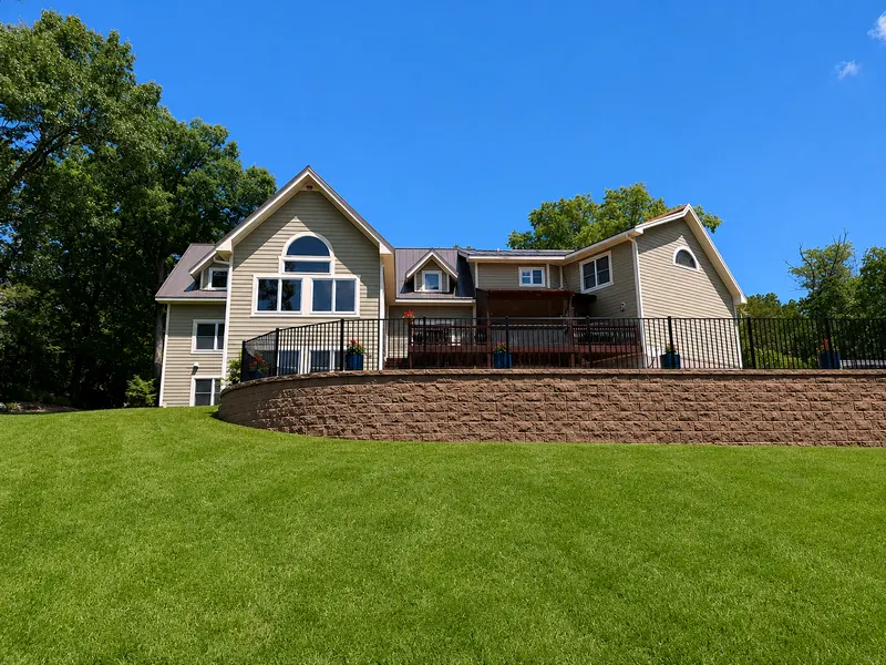 Large home with a standing seam metal roof above a curved retaining wall