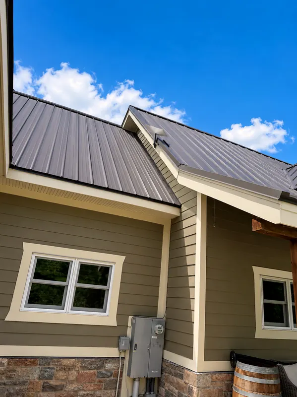 Close-up of standing seam metal roof panels and trim where two roof lines meet