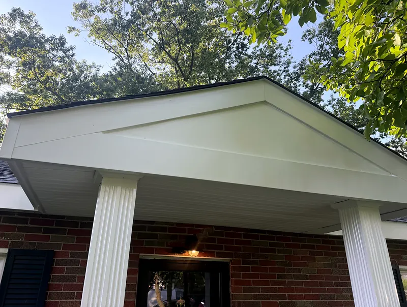 Close-up of a finished white porch gable, soffit and fascia trim