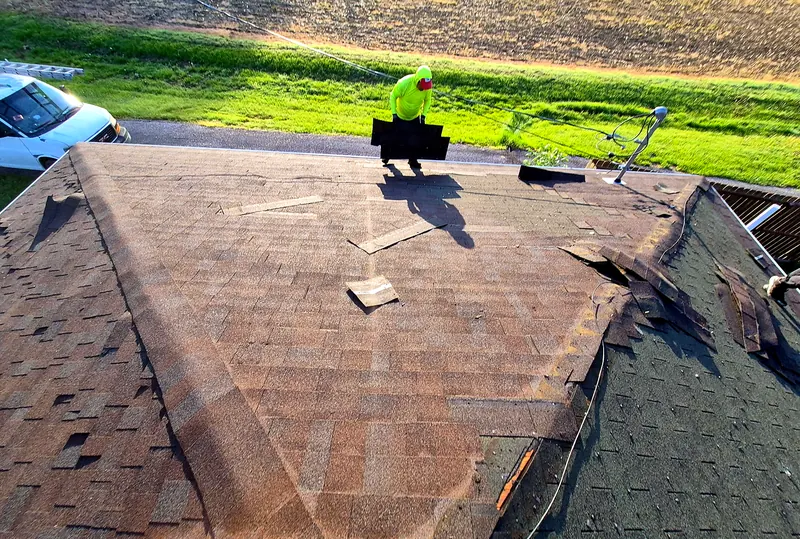 Prime Time Exteriors crew member carrying new shingles during a roof tear-off