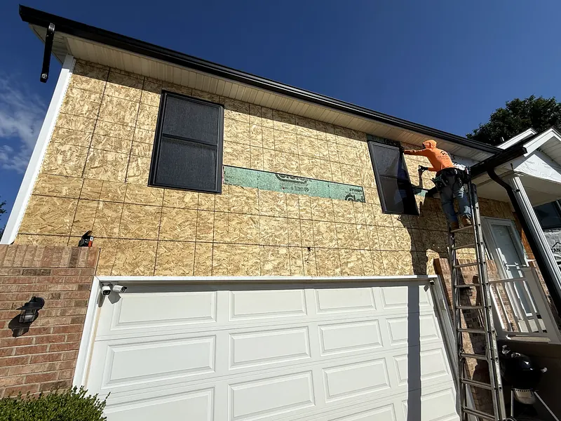 Crew member installing windows over new sheathing before siding goes on